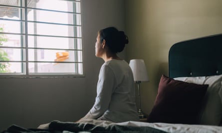 Une femme est assise sur le bord du lit après la fenêtre