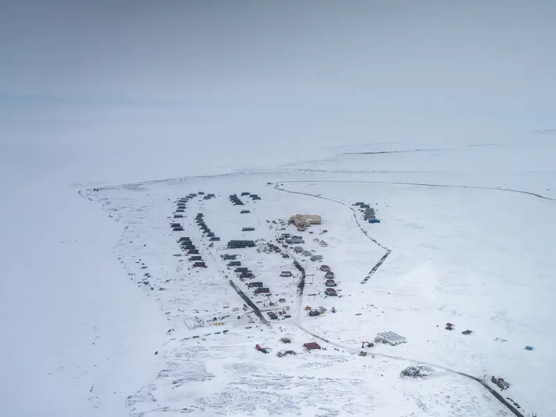Small, isolated buildings are surrounded by fields of snow.