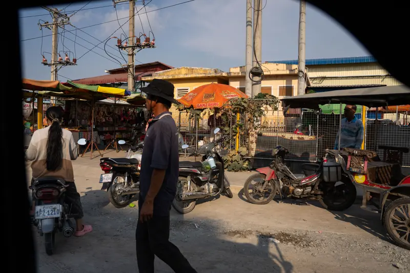 Les vélos à moteur, les personnes et les parapluies de table sont devant des bâtiments à l'étage.
