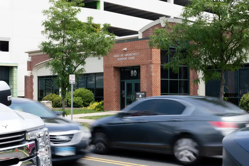 Cars drive past the Hartford housing court, a red-brick building.