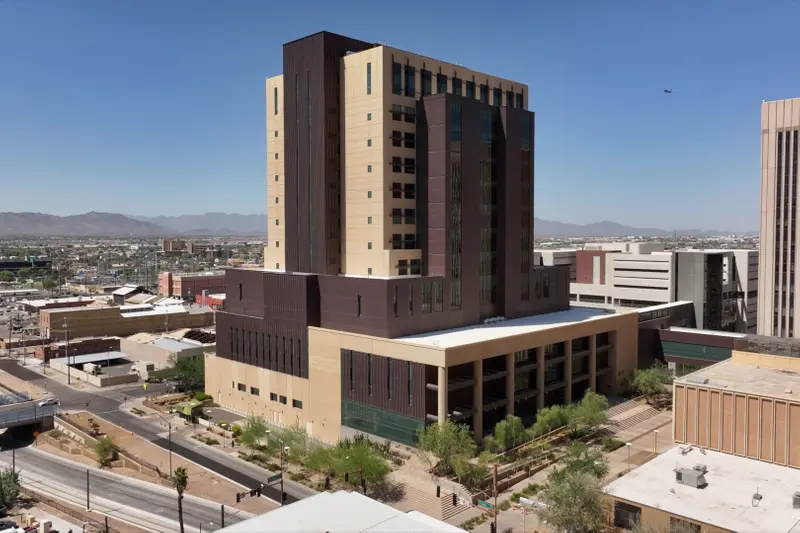 An aerial photograph showing a large tan and maroon courthouse building surrounded by other smaller buildings in downtown Phoenix, with low mountains in the background.