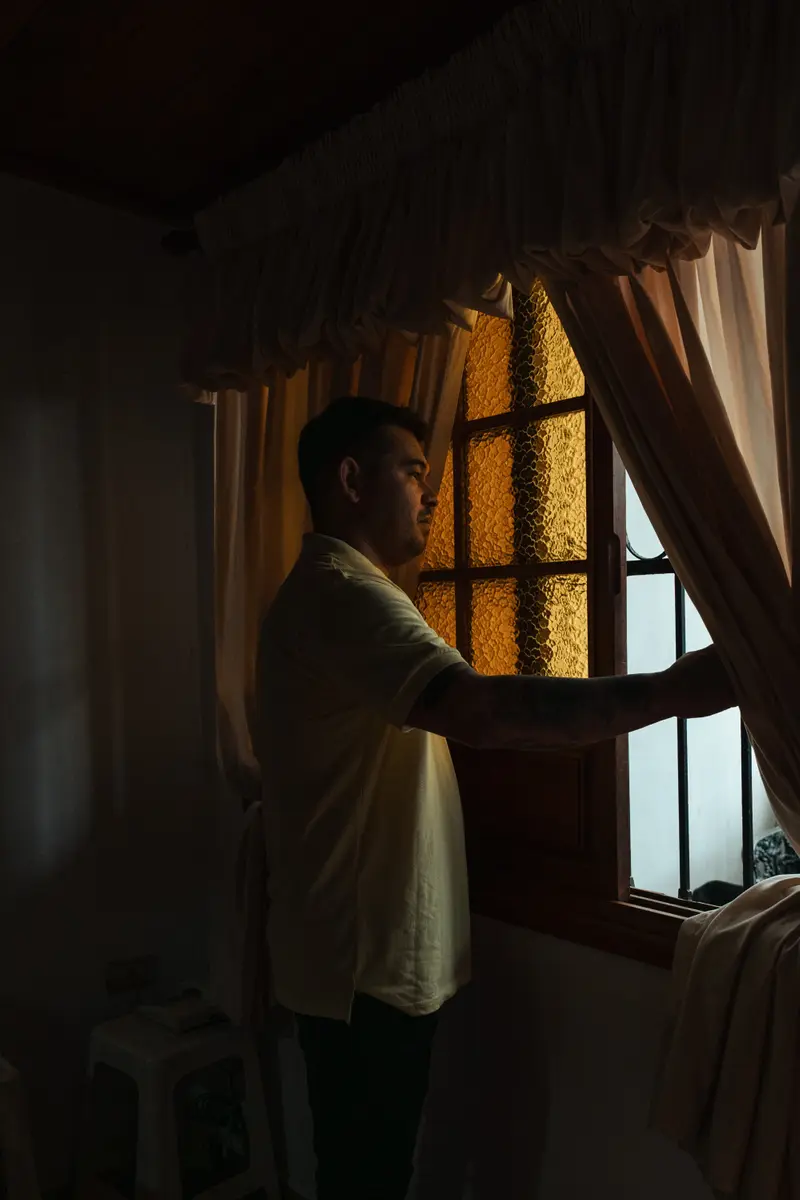 Andry Omar Blanco Bonilla looks out the window at his house.