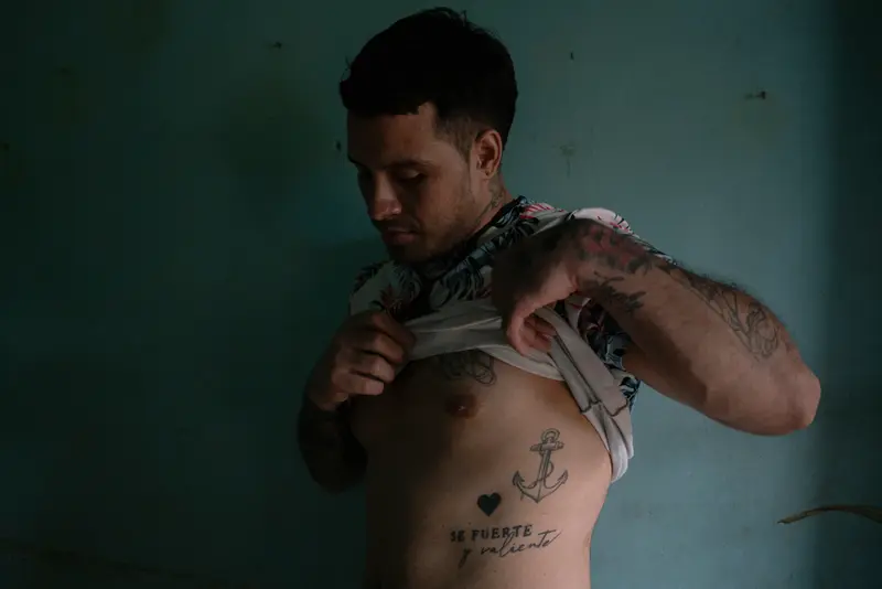 Rodríguez soulève sa chemise pour montrer certains de ses tatouages.