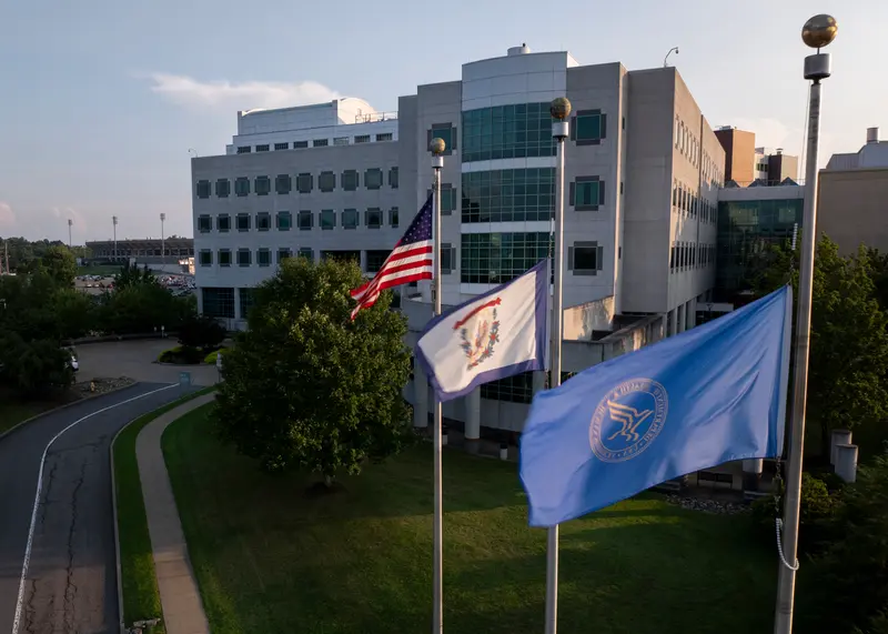 A building with three flags flying in the foreground: U.S., West Virginia and Department of Health and Human Services.