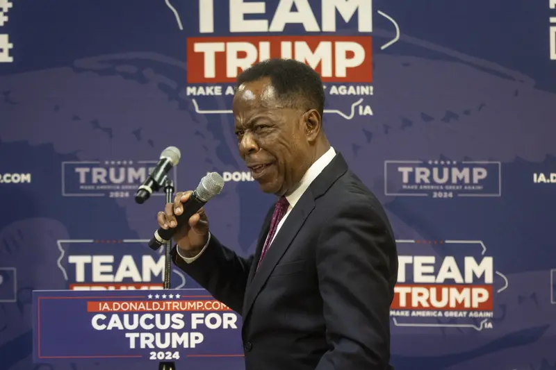 Terrell speaks into a microphone in front of a “Team Trump” backdrop.