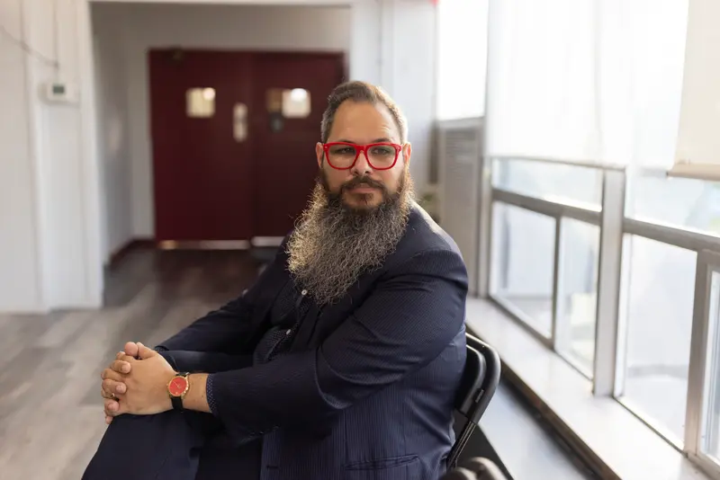 A man with bright red glasses poses for a portrait.