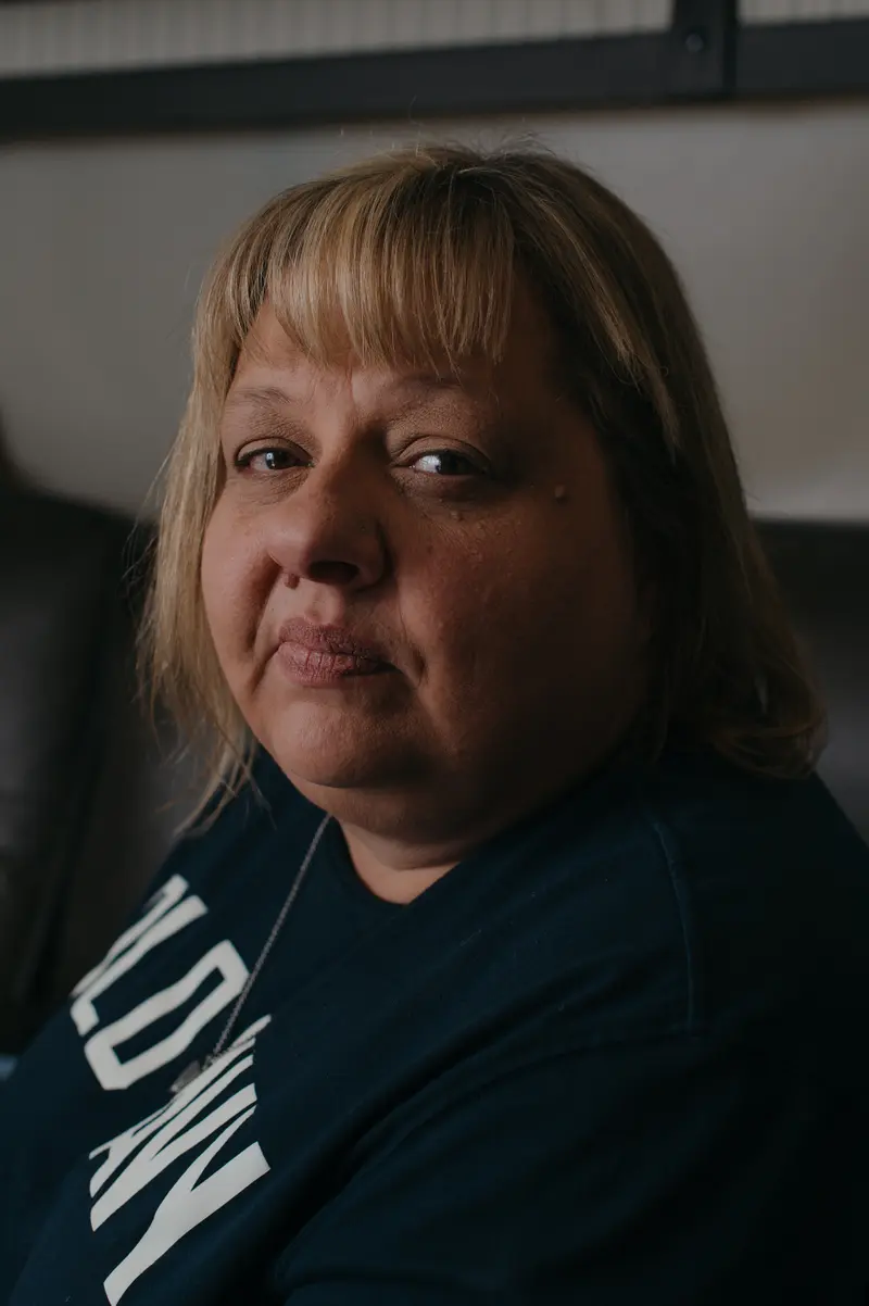 A woman with blond hair and bangs wearing an Old Navy T-shirt stares into the camera.