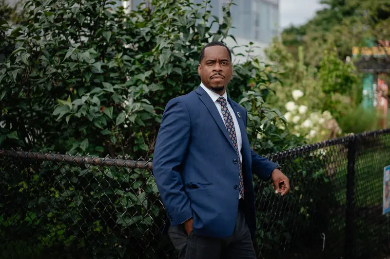 Chalmers Principal Romian Crockett leaning on a chainlink fence.