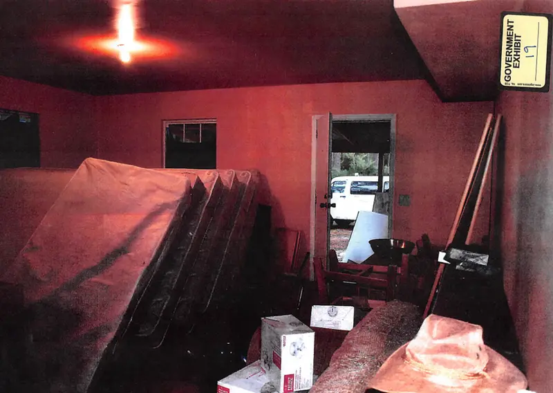A dimly lit red room filled with mattresses stacked vertically.