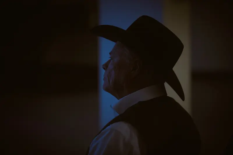 Maricopa County Sheriff Jerry Sheridan, wearing a cowboy hat, is lit by a soft blue glow in a dark room.