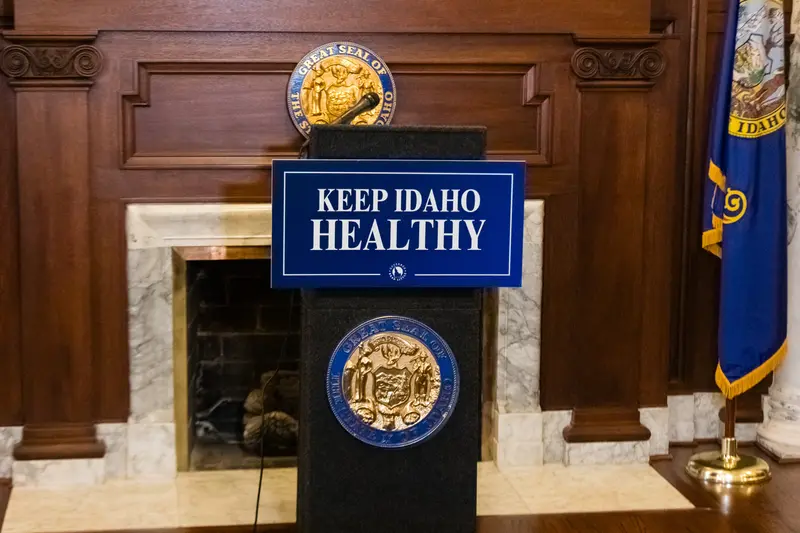A podium with the sign “Keep Idaho Healthy” sits in front of a wood and marble fireplace.