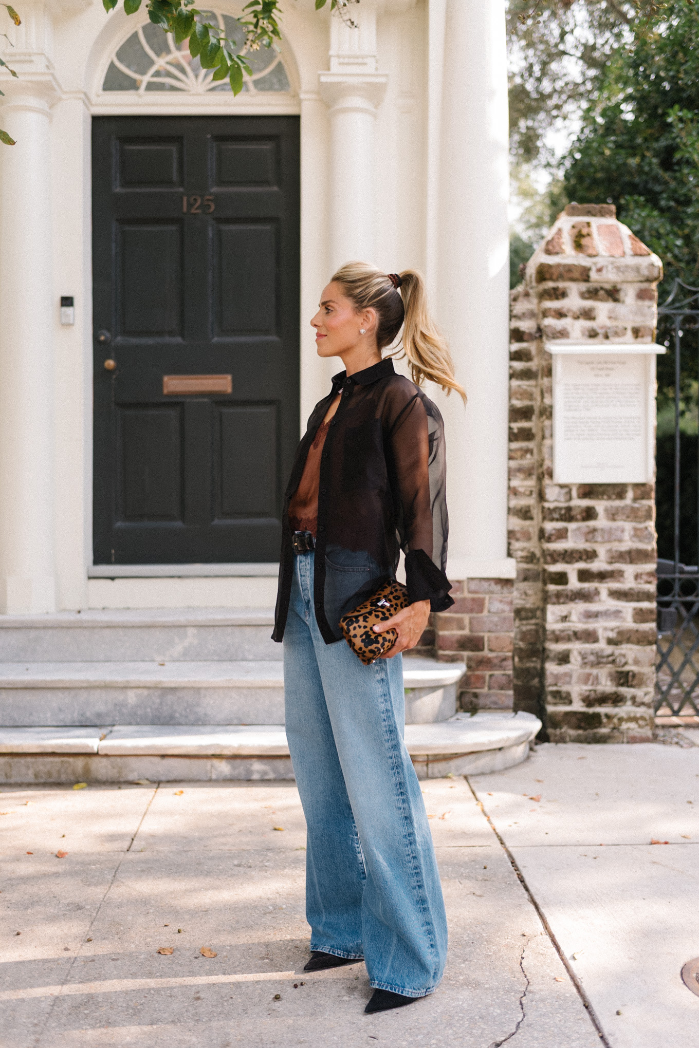 Blouse transparente noire, camisole en soie marron, jean bleu et pochette léopard