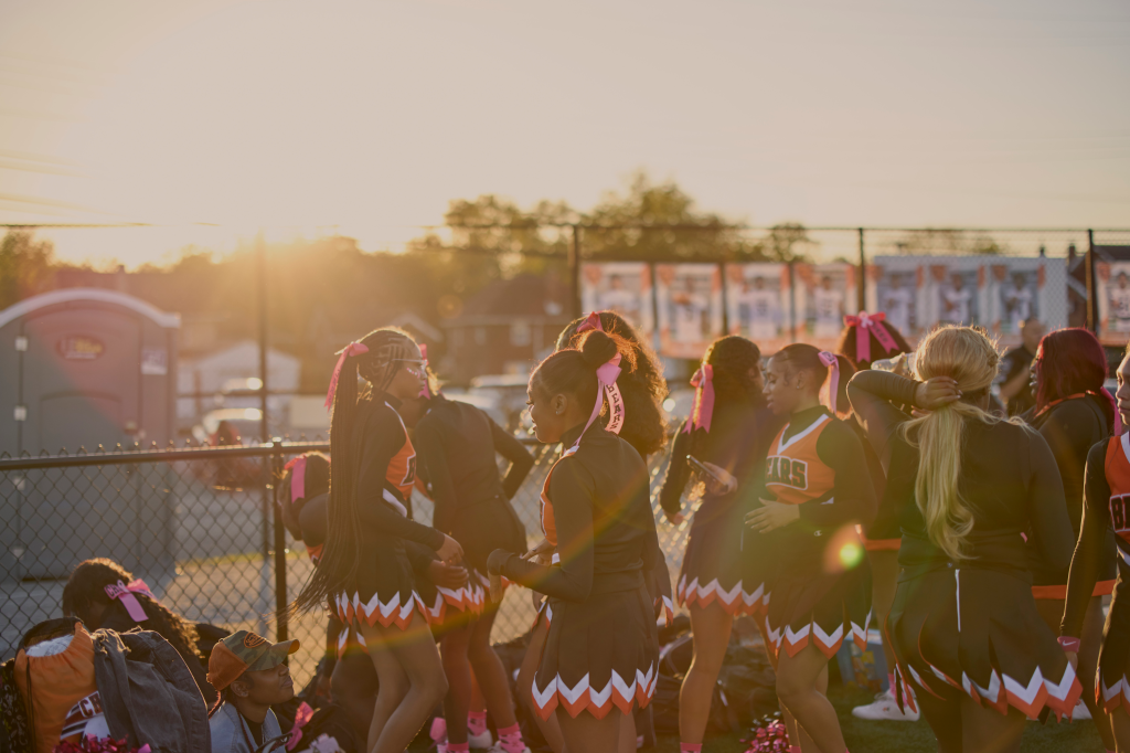 A warm beam of sun shines on a group of high school cheerleaders.