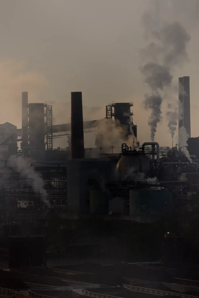 Steam rises from stacks and fills the air around an industrial facility.