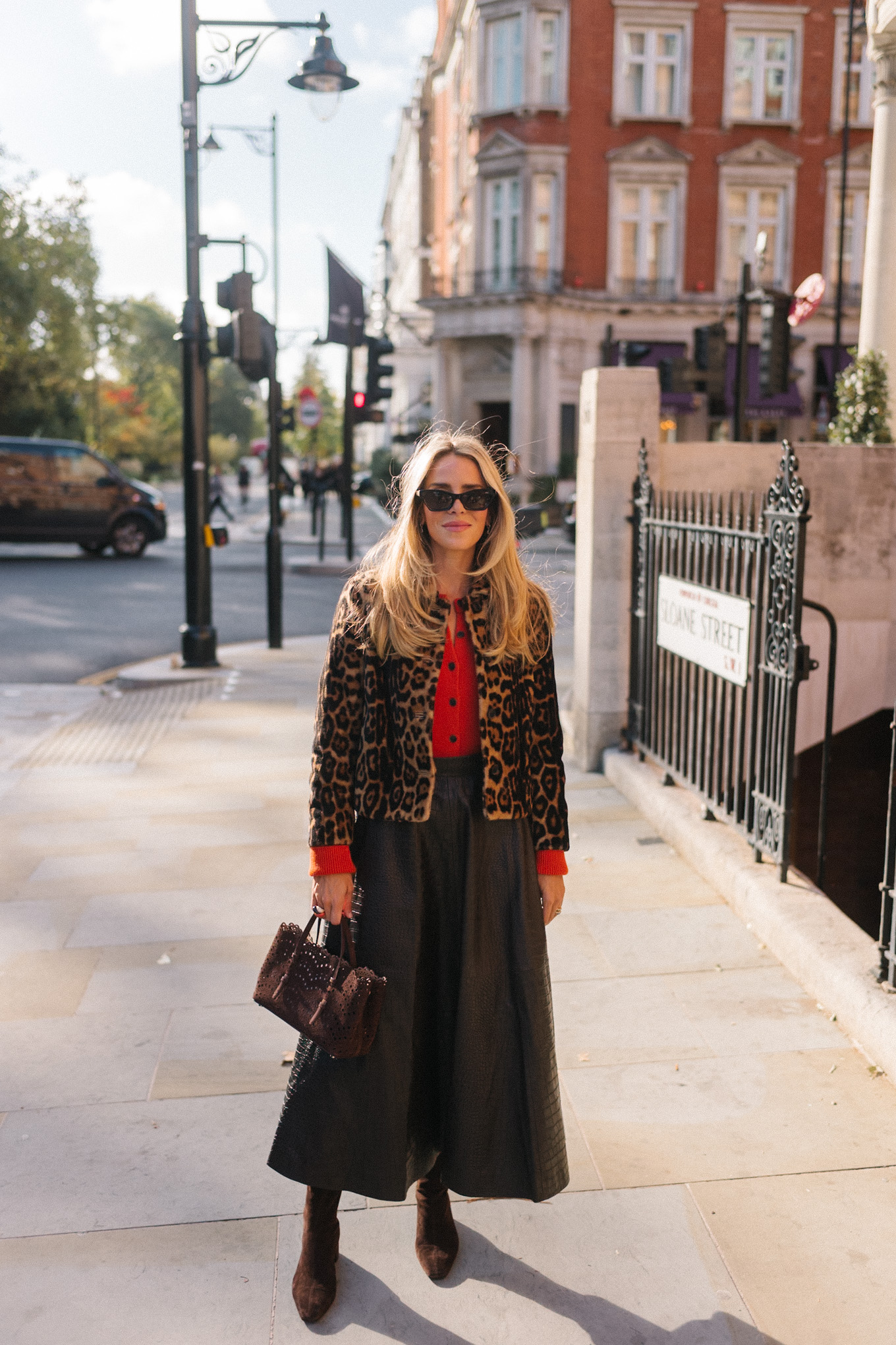 Veste en peau lainée à imprimé léopard, jupe longue marron, cardigan rouge-orange, bottes en daim