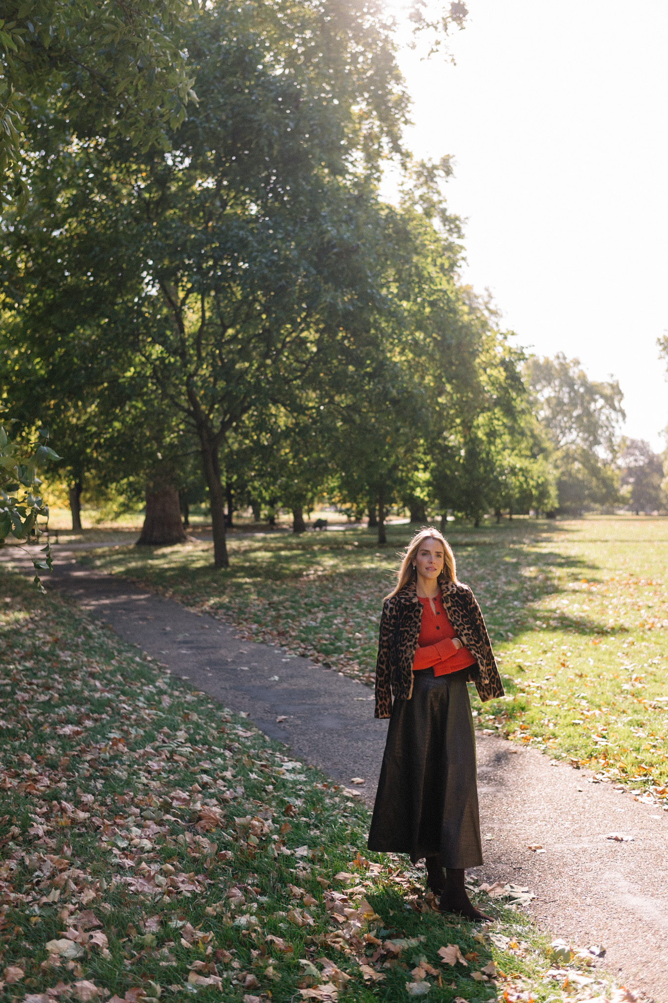 Veste en peau lainée à imprimé léopard, jupe longue marron, cardigan rouge-orange, bottes en daim