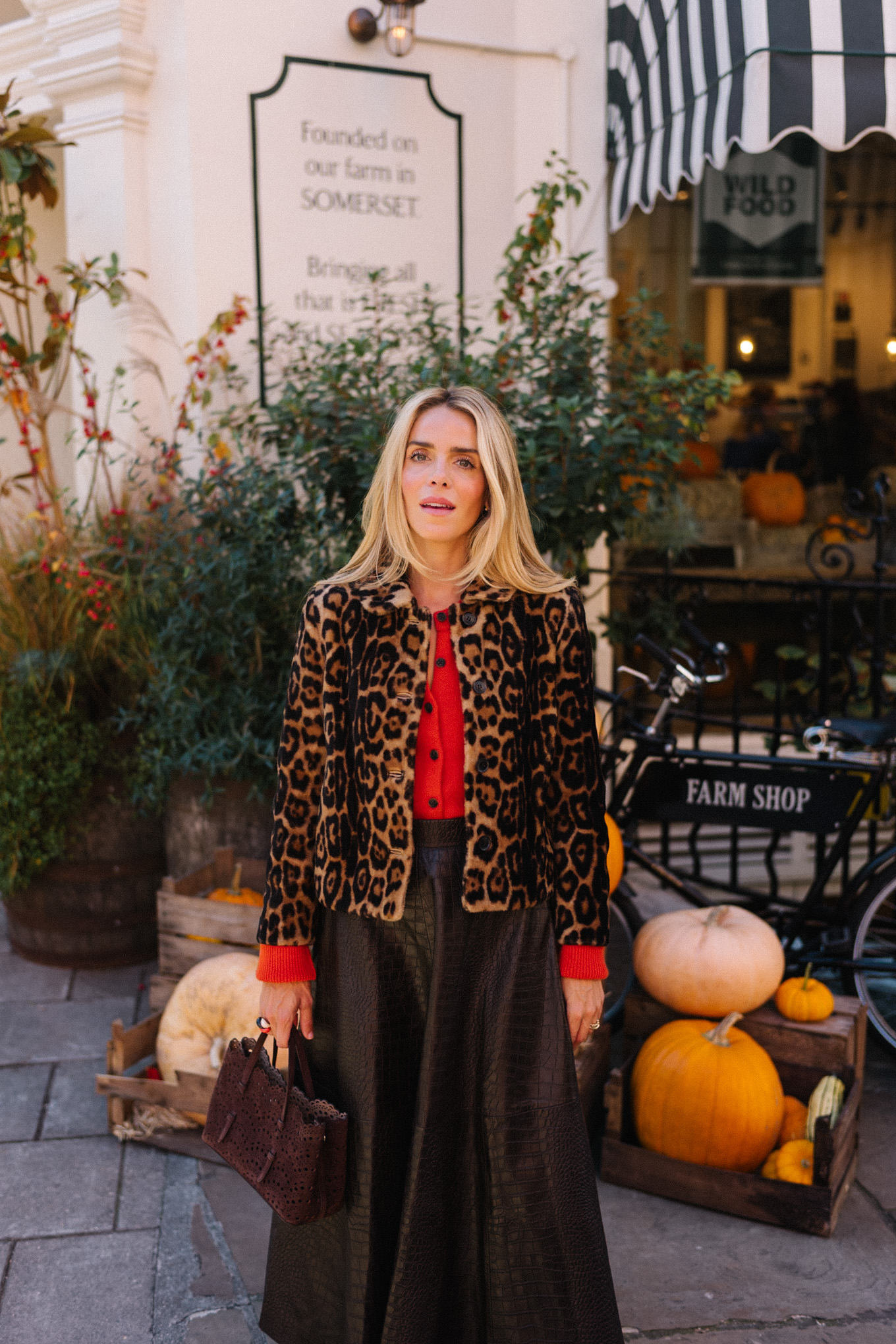 Veste en peau lainée à imprimé léopard, jupe longue marron, cardigan rouge-orange, bottes en daim
