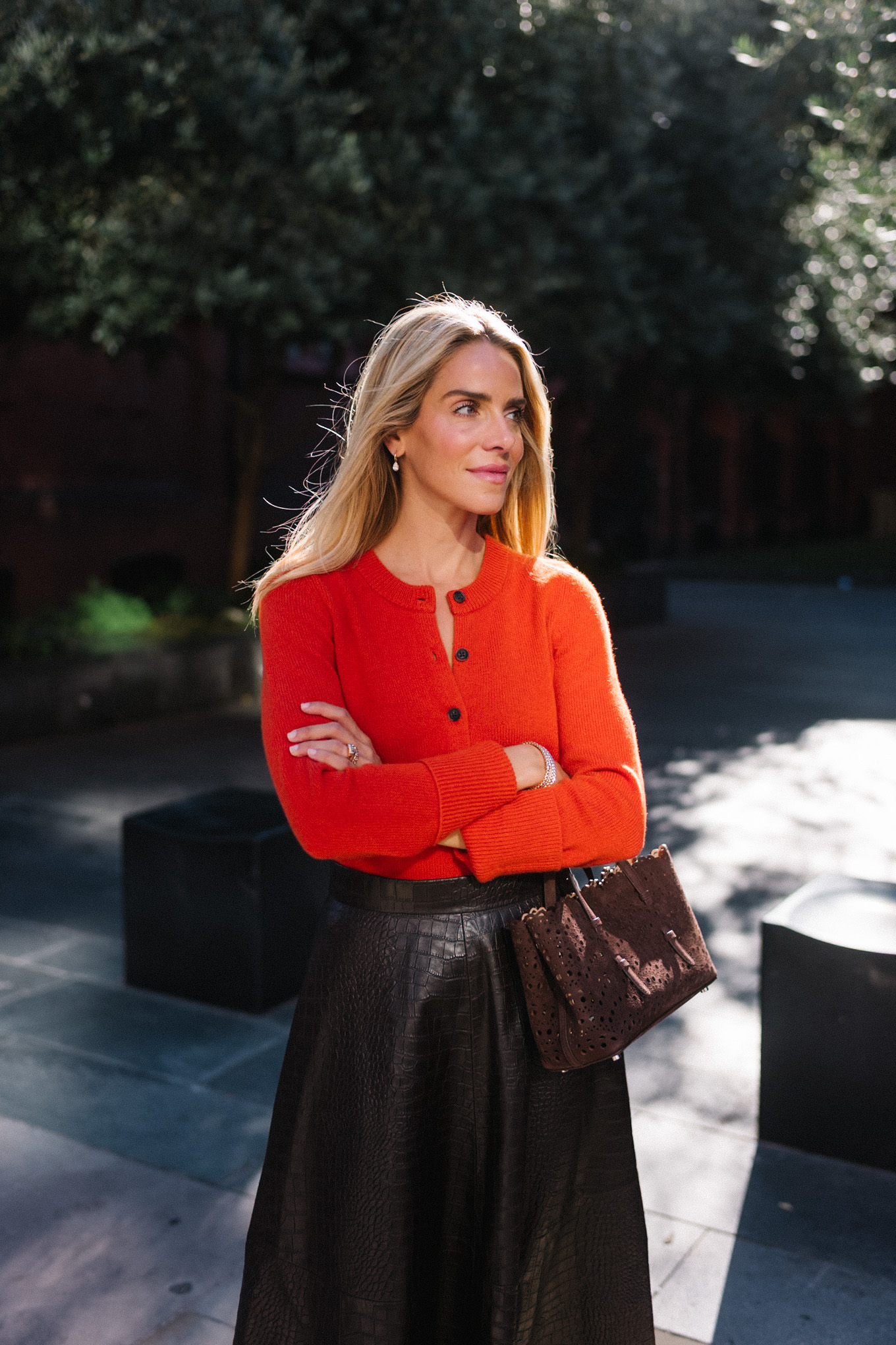 Veste en peau lainée à imprimé léopard, jupe longue marron, cardigan rouge-orange, bottes en daim