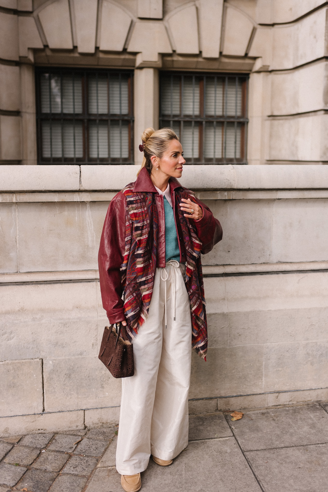 veste en cuir marron, écharpe rayée, pull turquoise, chemise boutonnée blanche, pantalon large crème
