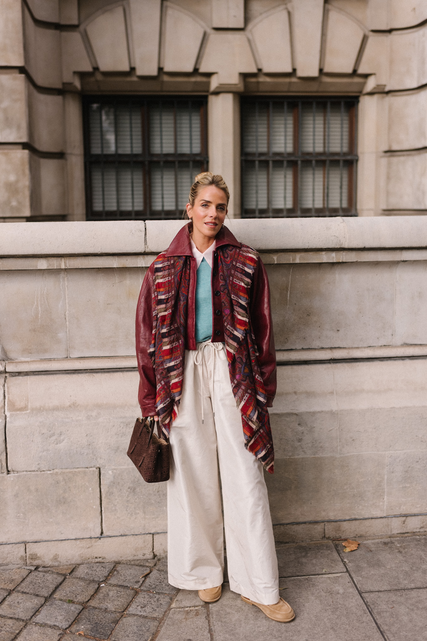 veste en cuir marron, écharpe rayée, pull turquoise, chemise boutonnée blanche, pantalon large crème