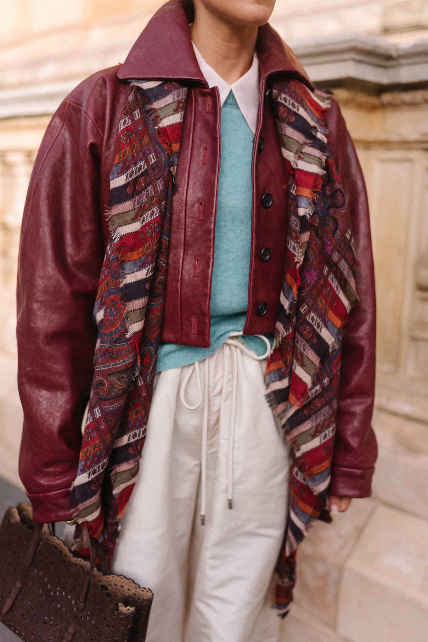 veste en cuir marron, écharpe rayée, pull turquoise, chemise boutonnée blanche, pantalon large crème