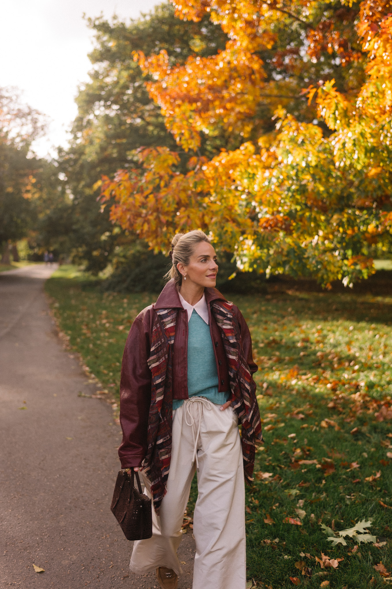 veste en cuir marron, écharpe rayée, pull turquoise, chemise boutonnée blanche, pantalon large crème