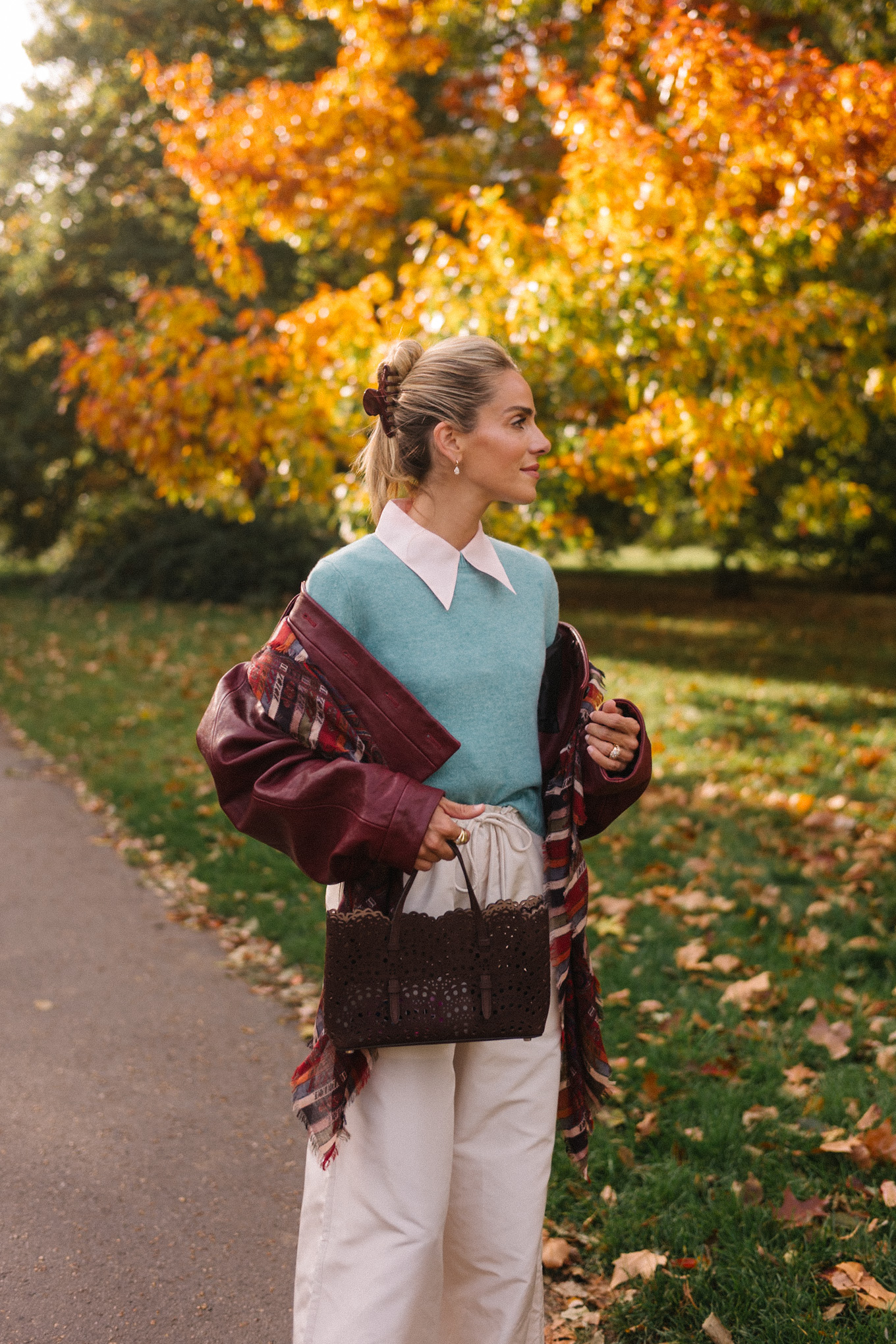 veste en cuir marron, écharpe rayée, pull turquoise, chemise boutonnée blanche, pantalon large crème