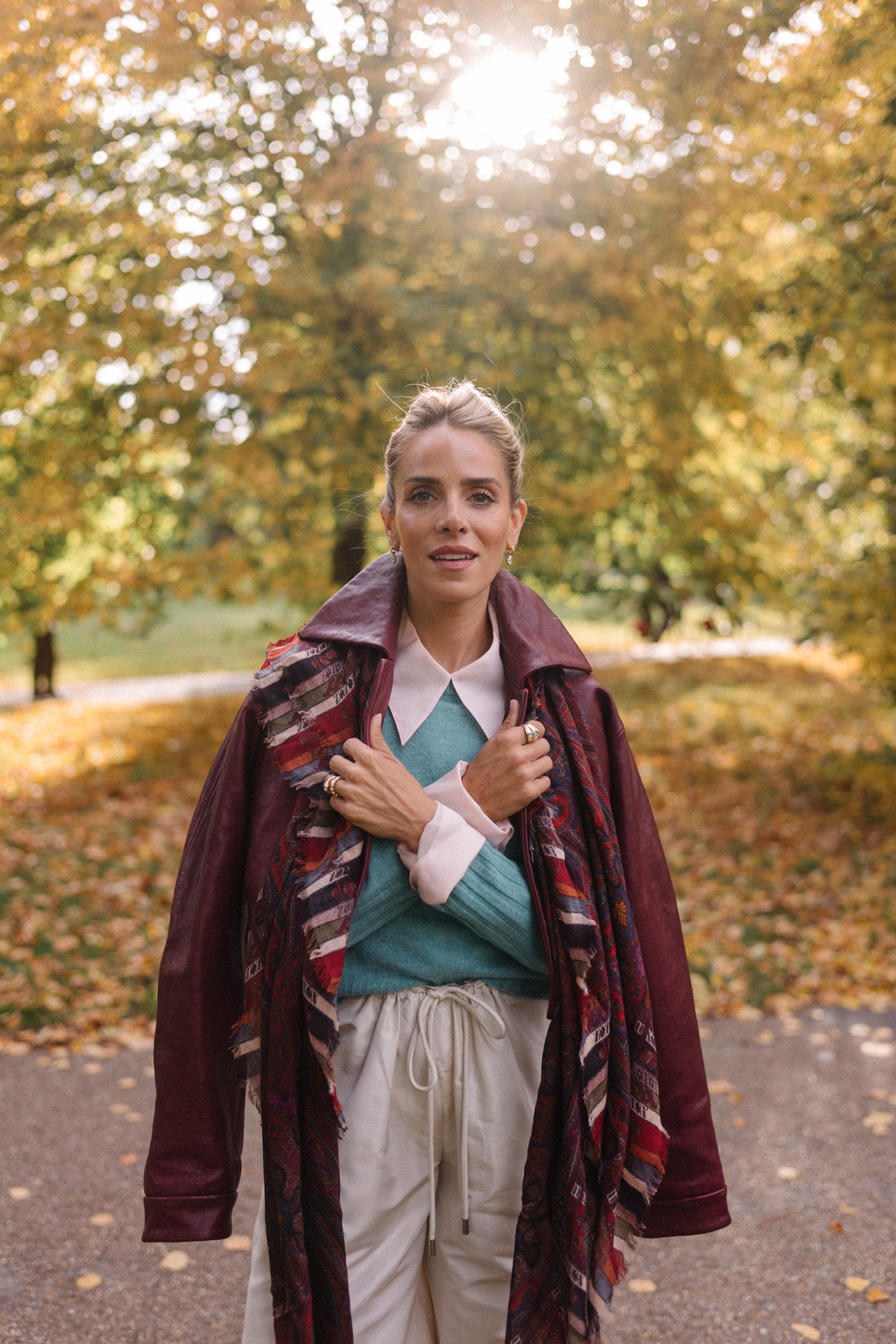 veste en cuir marron, écharpe rayée, pull turquoise, chemise boutonnée blanche, pantalon large crème