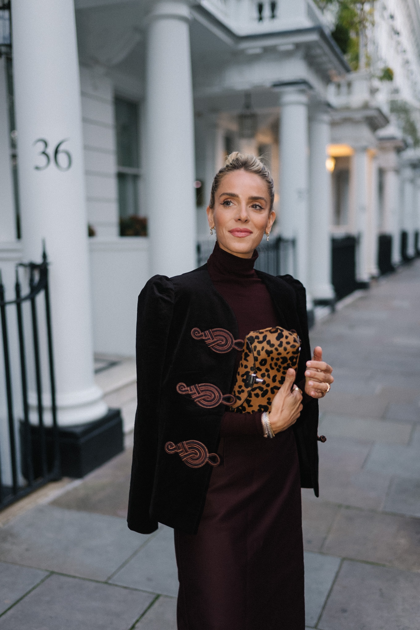 Blazer en velours noir, col roulé marron, jupe à franges en soie marron, pochette léopard, escarpins texturés
