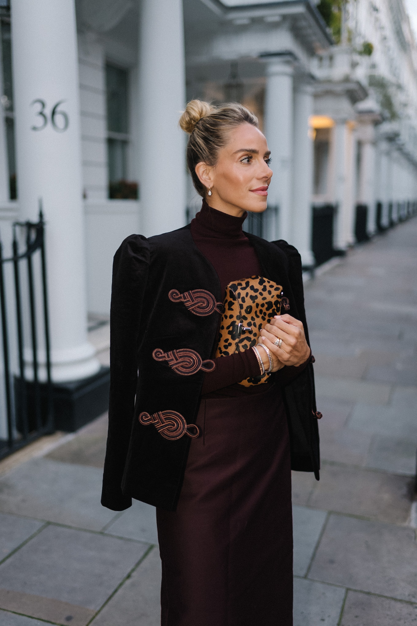 Blazer en velours noir, col roulé marron, jupe à franges en soie marron, pochette léopard, escarpins texturés