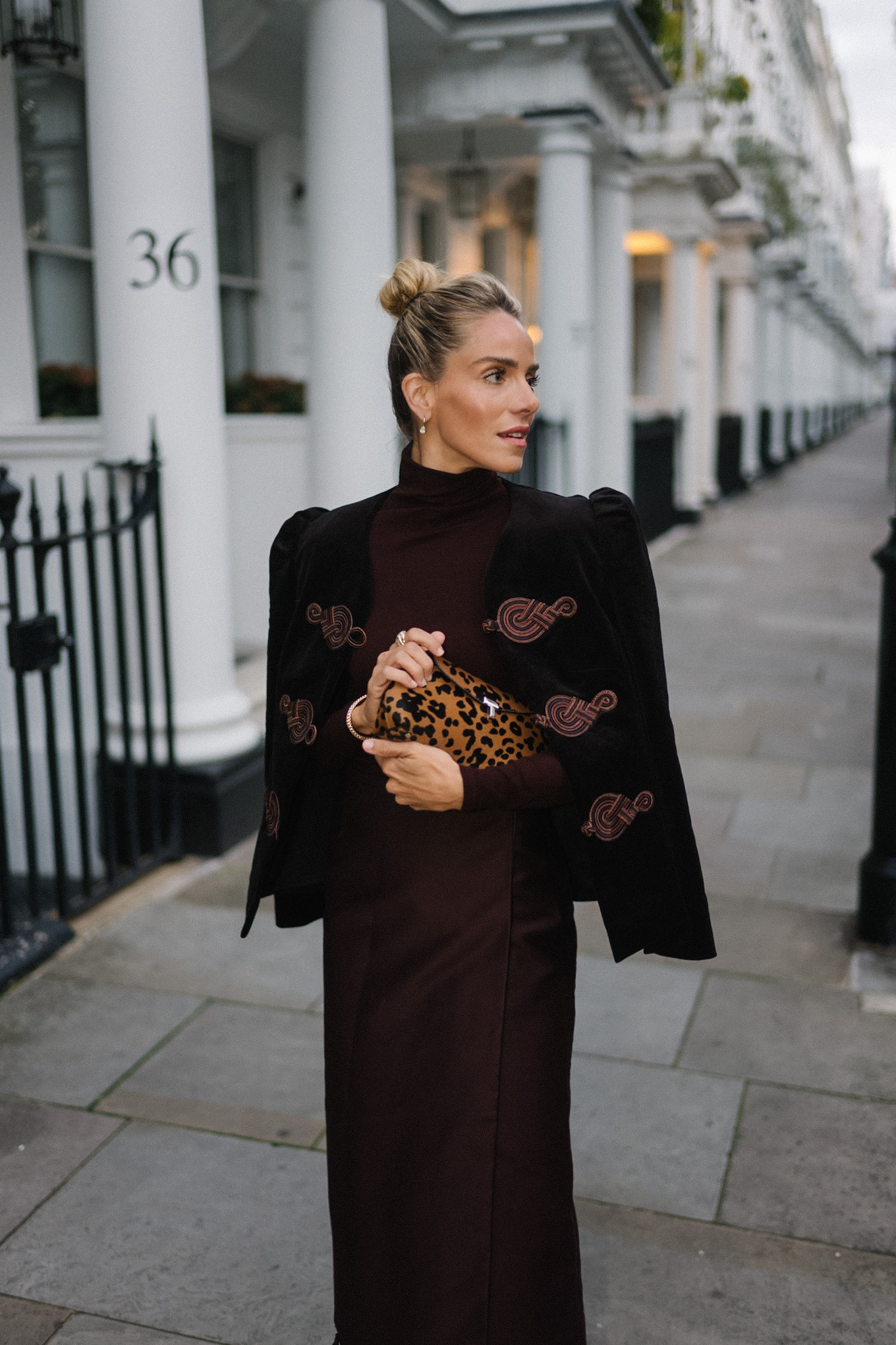 Blazer en velours noir, col roulé marron, jupe à franges en soie marron, pochette léopard, escarpins texturés