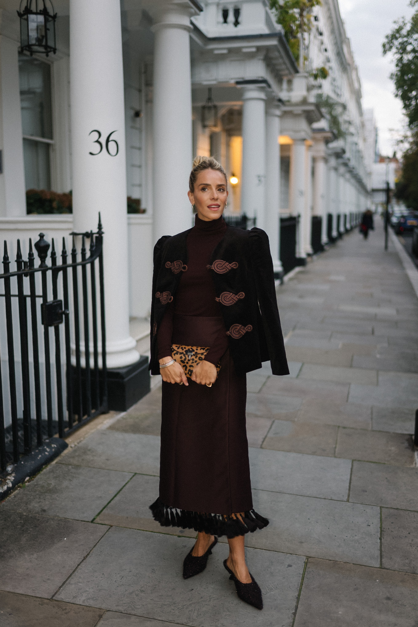 Blazer en velours noir, col roulé marron, jupe à franges en soie marron, pochette léopard, escarpins texturés