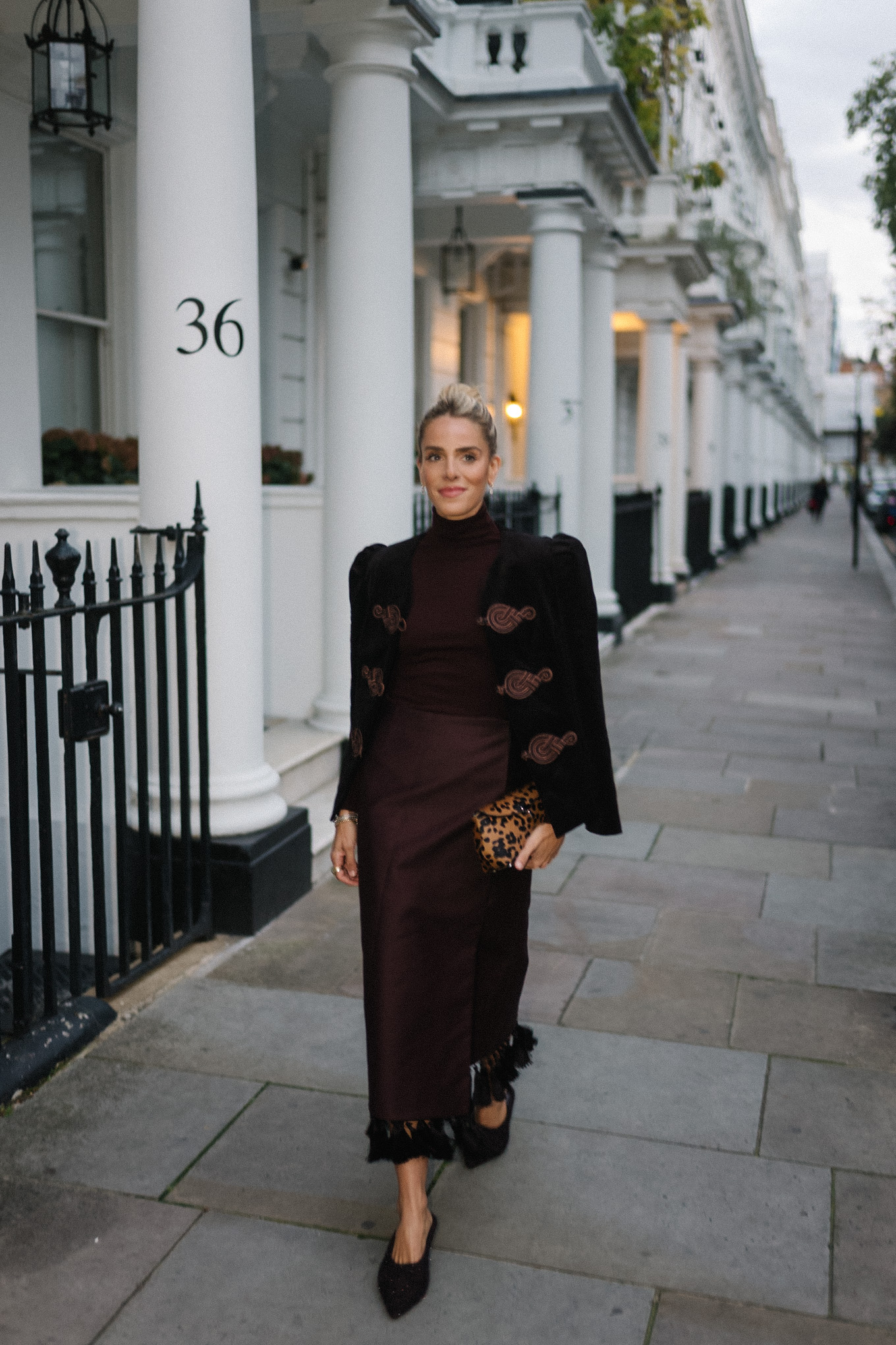 Blazer en velours noir, col roulé marron, jupe à franges en soie marron, pochette léopard, escarpins texturés