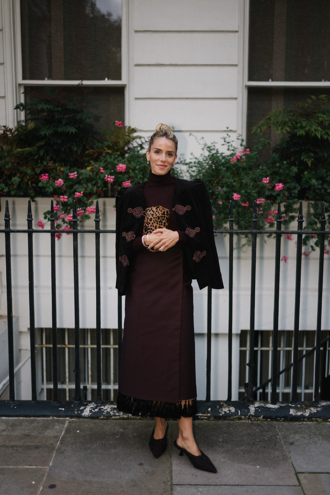 Blazer en velours noir, col roulé marron, jupe à franges en soie marron, pochette léopard, escarpins texturés