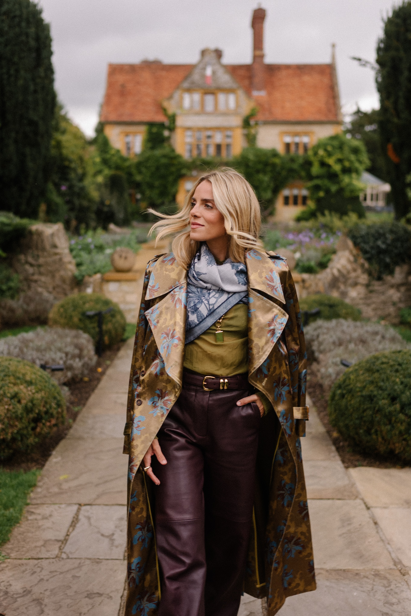 Blouse transparente verte, pantalon en cuir marron, écharpe bleue, trench jacquard