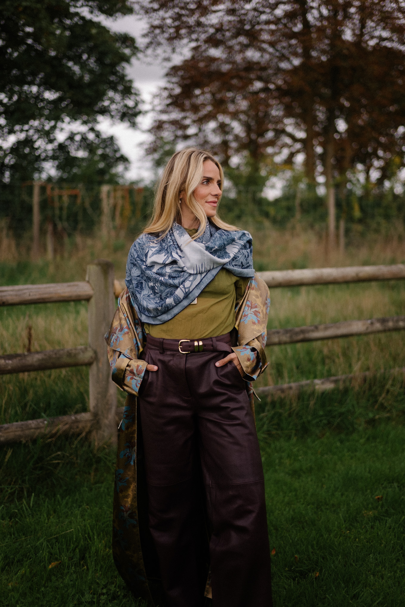 Blouse transparente verte, pantalon en cuir marron, écharpe bleue, trench jacquard