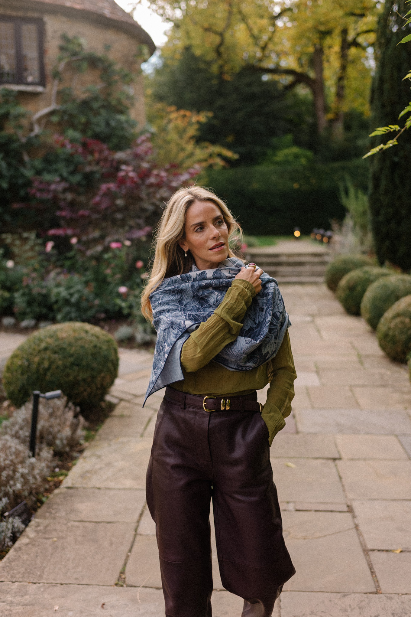 Blouse transparente verte, pantalon en cuir marron, écharpe bleue, trench jacquard