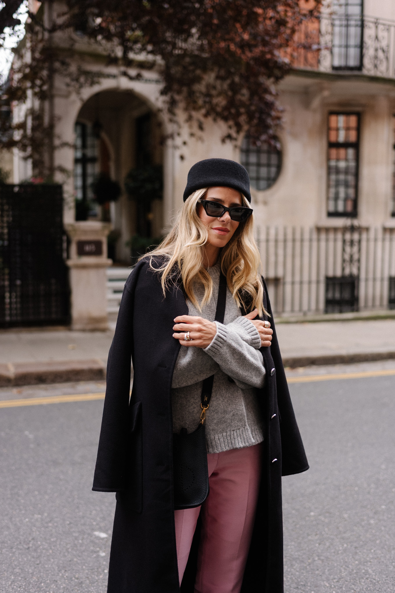 manteau en laine noire, cardigan gris, pantalon en satin rose, chapeau casemate en laine noire