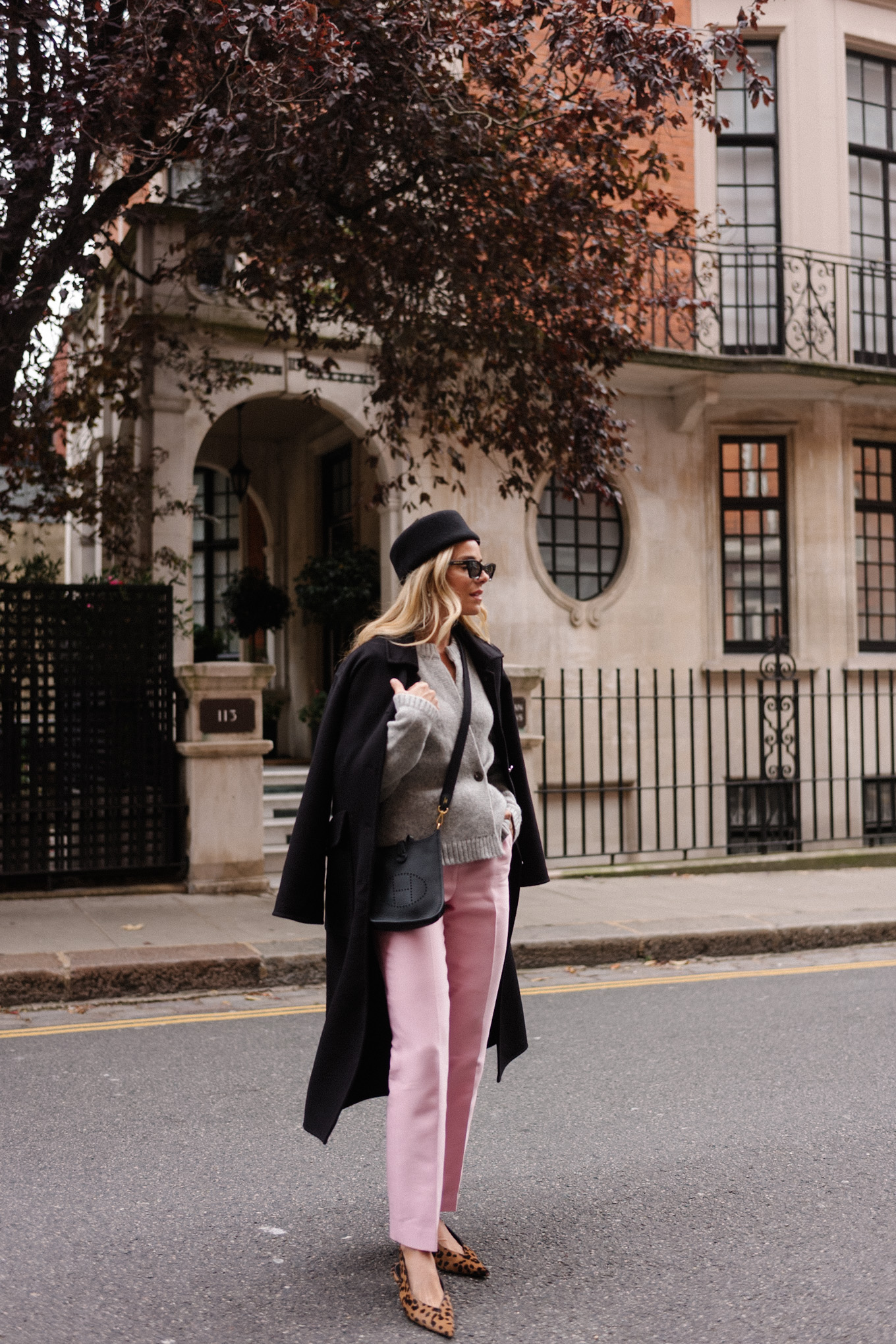 manteau en laine noire, cardigan gris, pantalon en satin rose, chapeau casemate en laine noire