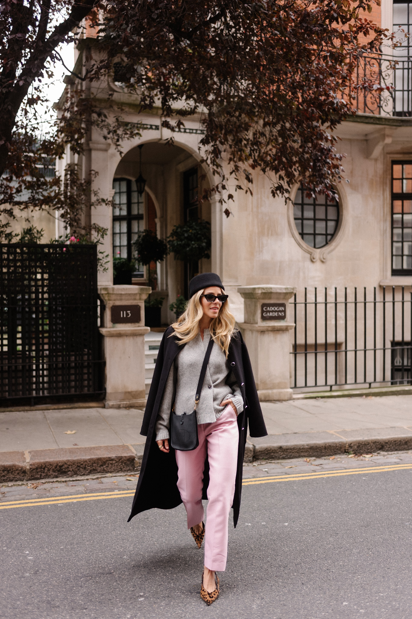 manteau en laine noire, cardigan gris, pantalon en satin rose, chapeau casemate en laine noire