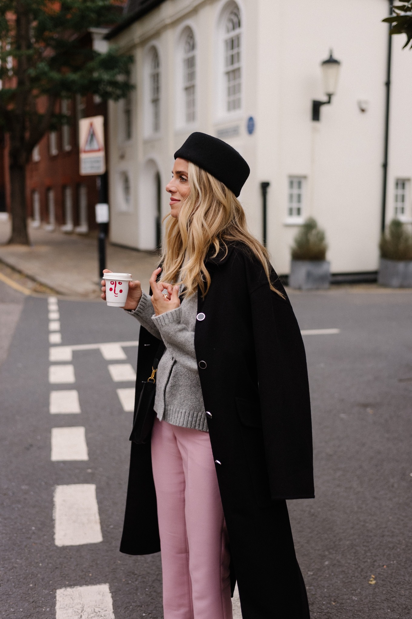 manteau en laine noire, cardigan gris, pantalon en satin rose, chapeau casemate en laine noire