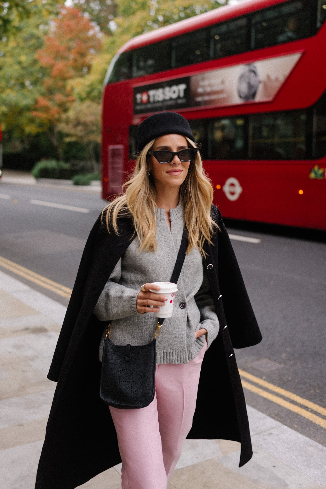 manteau en laine noire, cardigan gris, pantalon en satin rose, chapeau casemate en laine noire