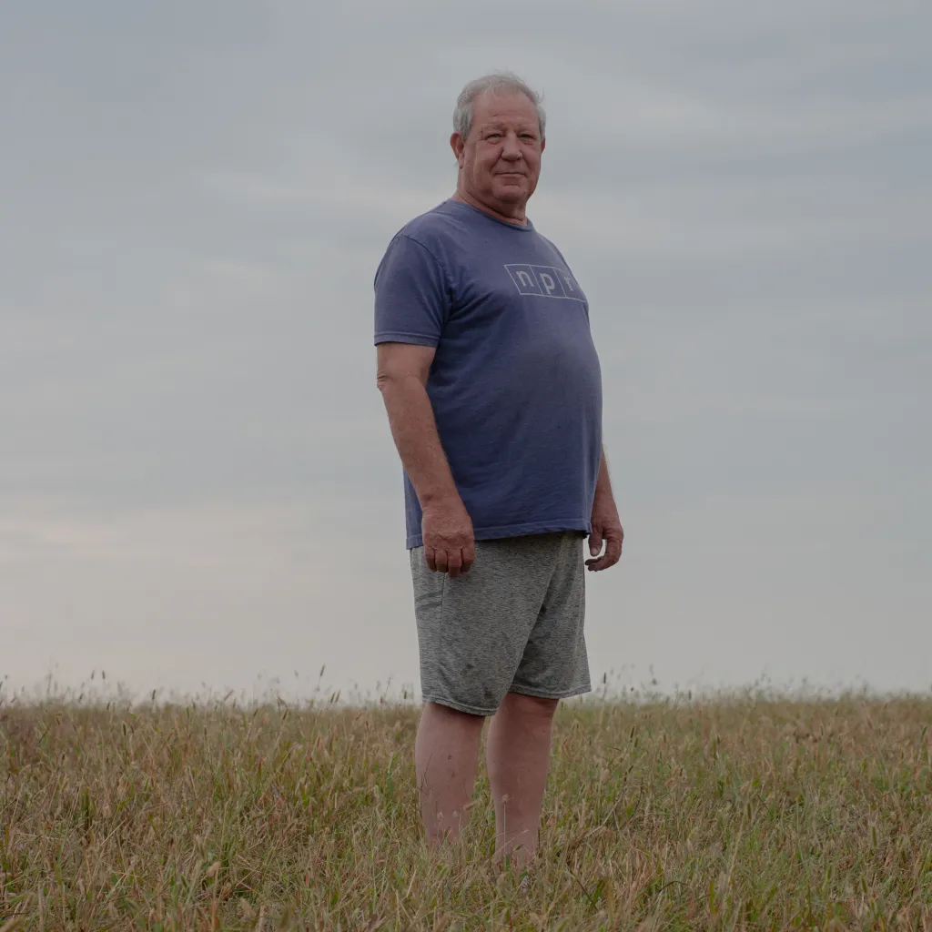 A man wearing a T-shirt and shorts standing in a field.