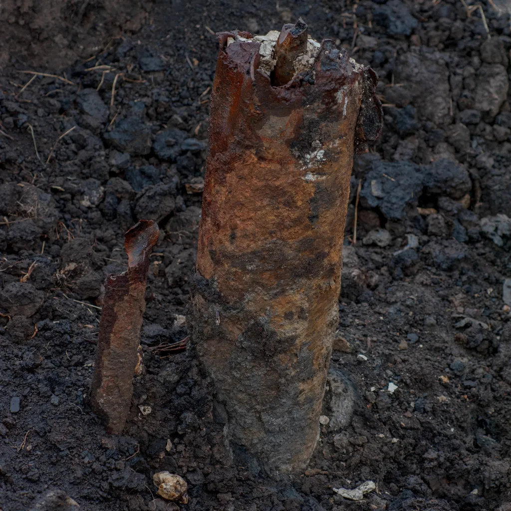 A rusty stub of pipe sticking straight up out of the ground.
