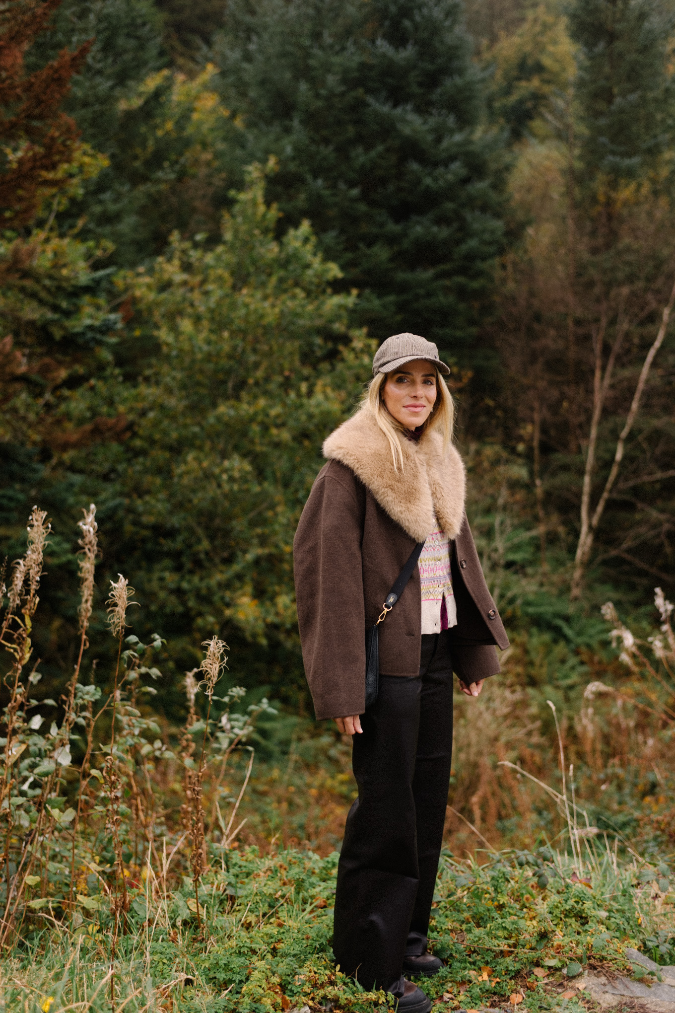 manteau en laine marron, écharpe avec col en fausse fourrure, pantalon en cuir noir, cardigan en cachemire