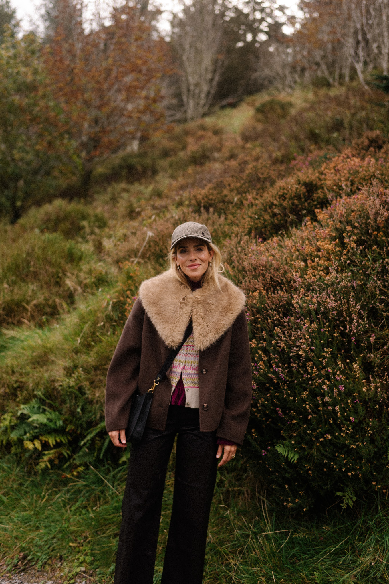 manteau en laine marron, écharpe avec col en fausse fourrure, pantalon en cuir noir, cardigan en cachemire