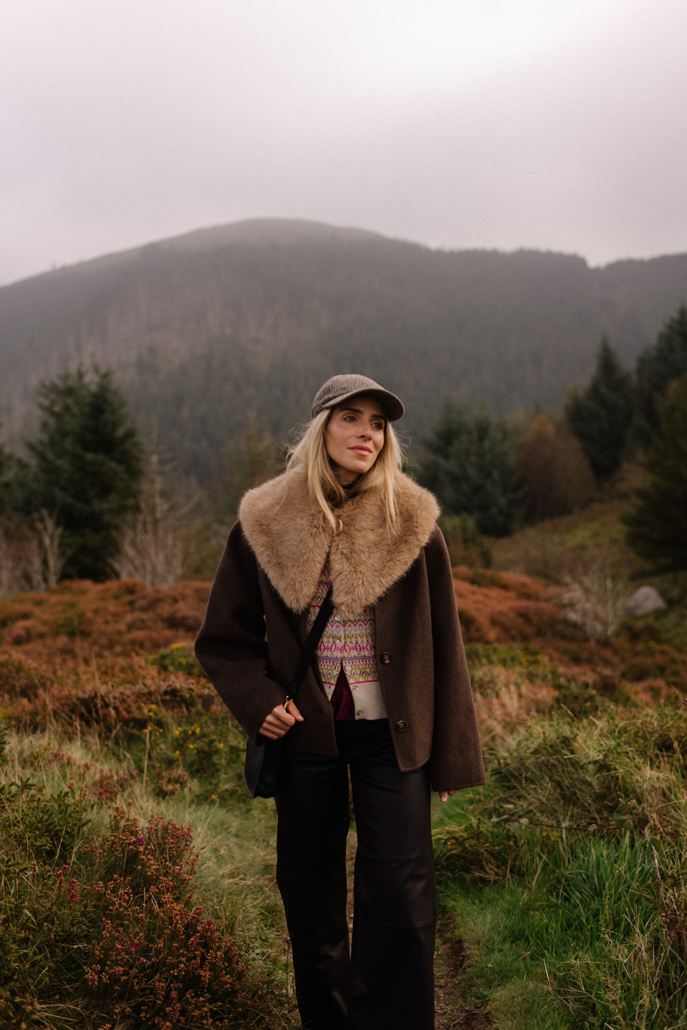 manteau en laine marron, écharpe avec col en fausse fourrure, pantalon en cuir noir, cardigan en cachemire