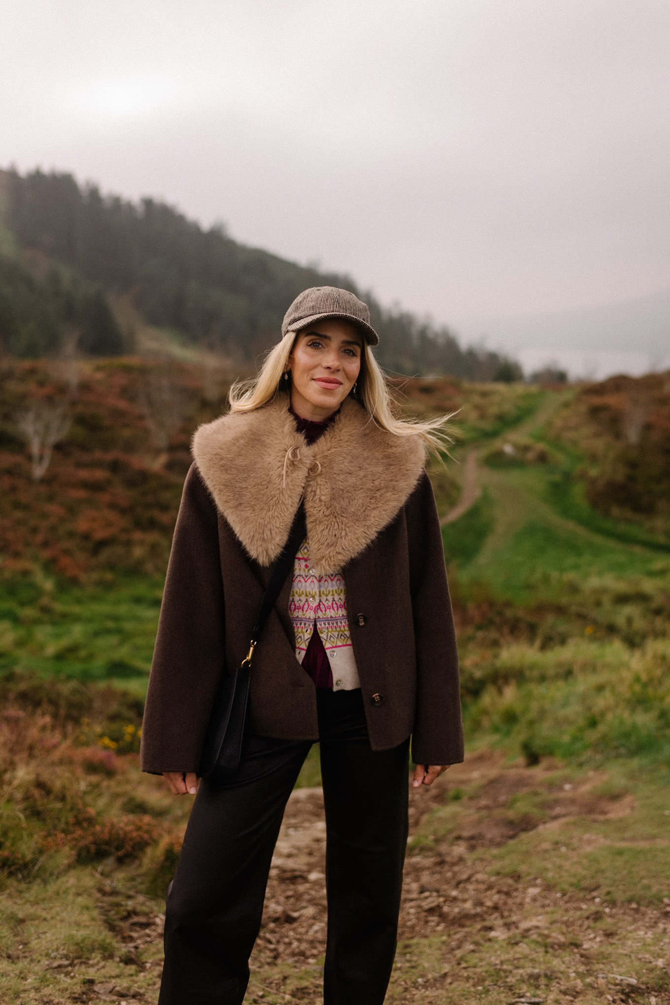 manteau en laine marron, écharpe avec col en fausse fourrure, pantalon en cuir noir, cardigan en cachemire