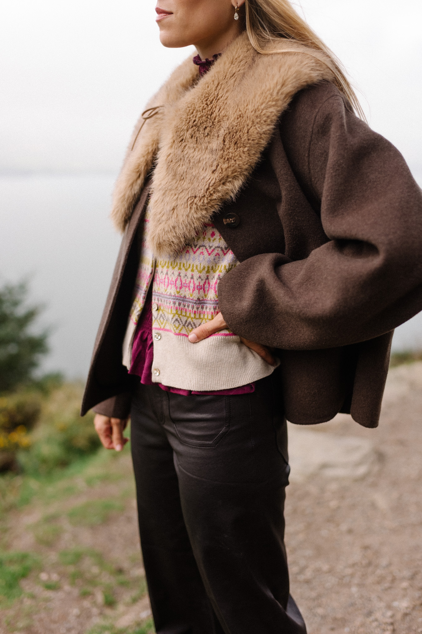manteau en laine marron, écharpe avec col en fausse fourrure, pantalon en cuir noir, cardigan en cachemire
