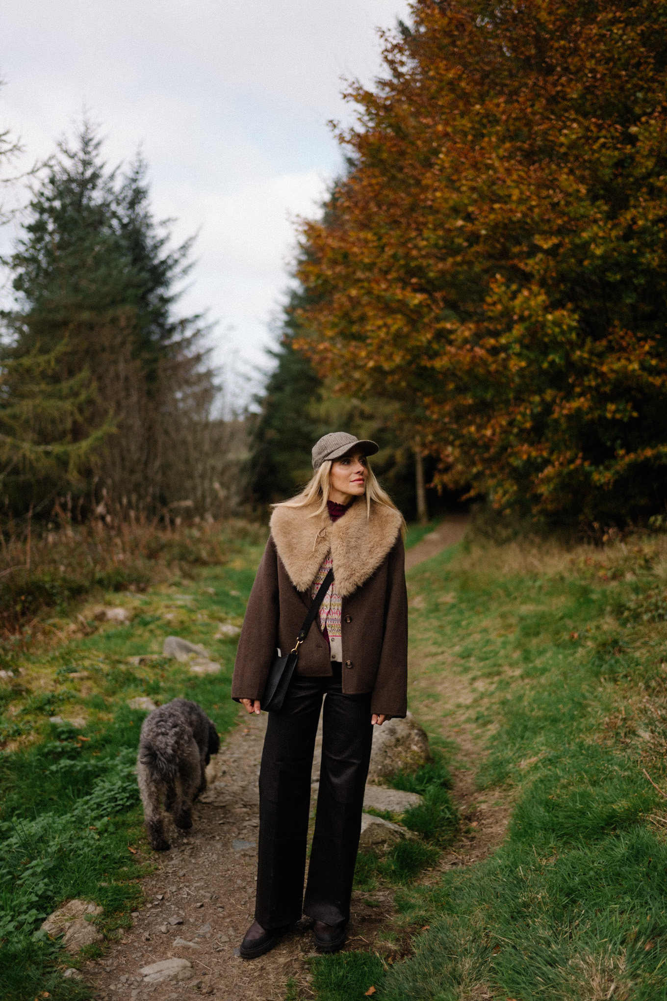 manteau en laine marron, écharpe avec col en fausse fourrure, pantalon en cuir noir, cardigan en cachemire